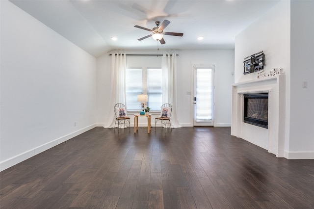 interior space featuring lofted ceiling, baseboards, dark wood-style flooring, and a glass covered fireplace