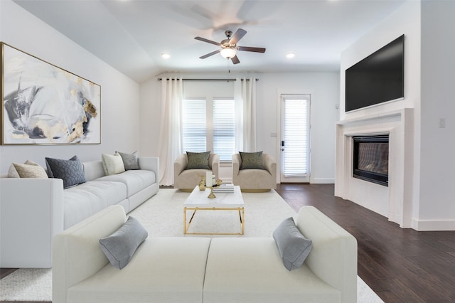 living room featuring baseboards, a glass covered fireplace, lofted ceiling, wood finished floors, and recessed lighting