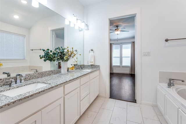 full bathroom featuring marble finish floor, a garden tub, a sink, and double vanity