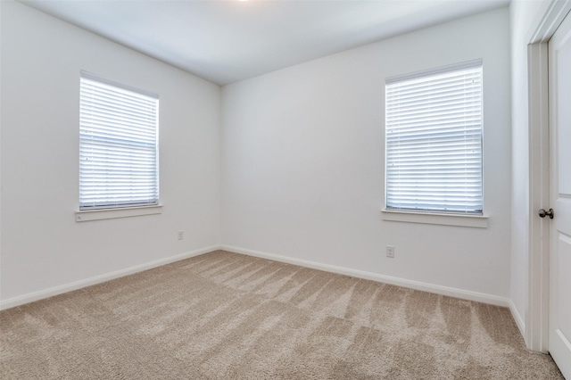 empty room featuring light carpet and baseboards