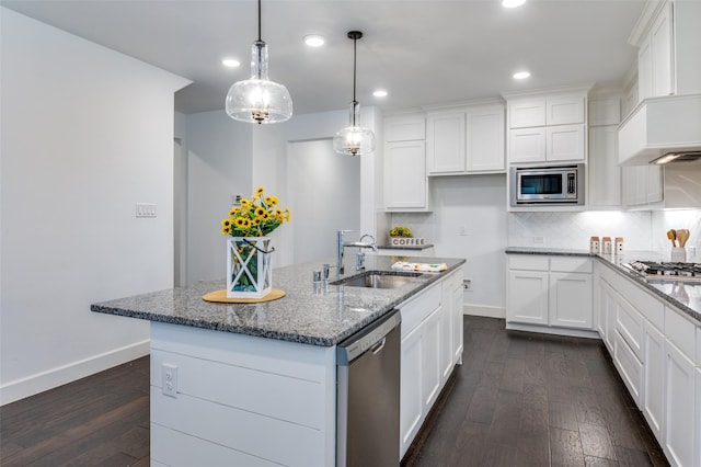 kitchen with dark wood finished floors, decorative backsplash, custom range hood, appliances with stainless steel finishes, and a sink