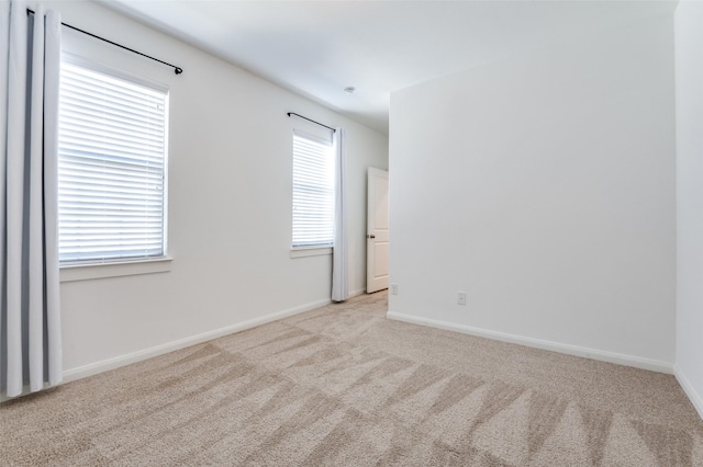 unfurnished room with light carpet and baseboards