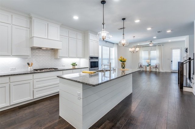 kitchen featuring visible vents, custom range hood, appliances with stainless steel finishes, dark wood-type flooring, and light stone countertops