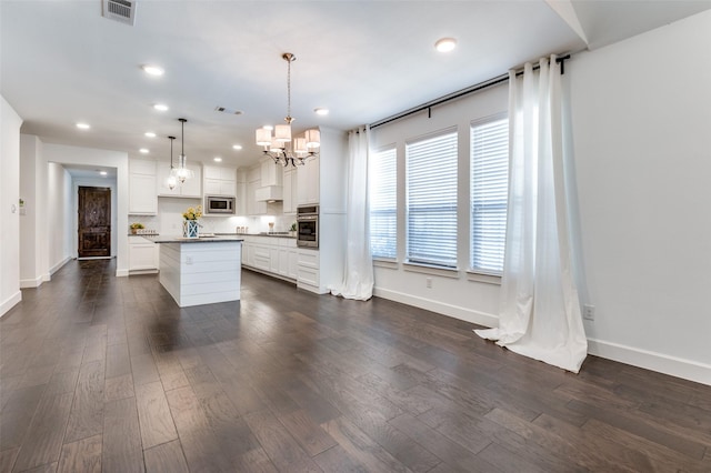 kitchen with appliances with stainless steel finishes, dark wood finished floors, visible vents, and a center island