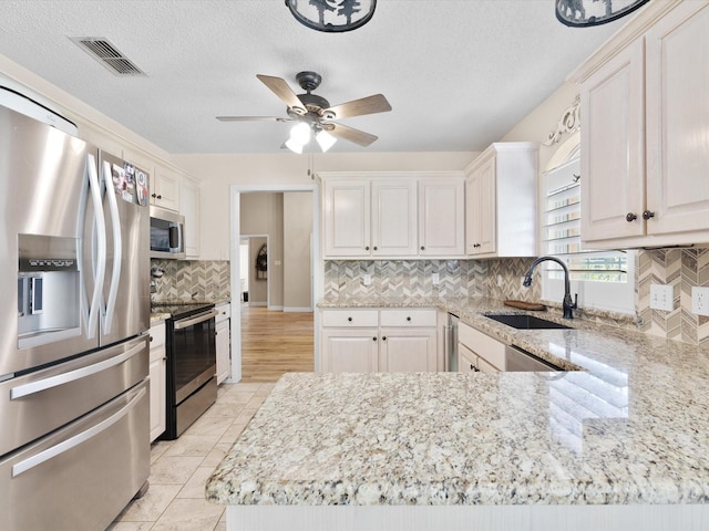 kitchen featuring stainless steel appliances, visible vents, a sink, and light stone counters