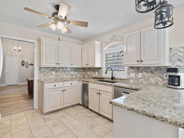 kitchen with backsplash, a sink, light stone countertops, a textured ceiling, and stainless steel dishwasher