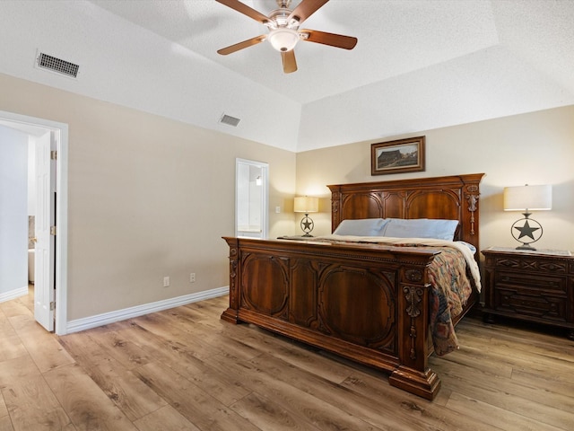 bedroom with light wood-type flooring, baseboards, visible vents, and vaulted ceiling