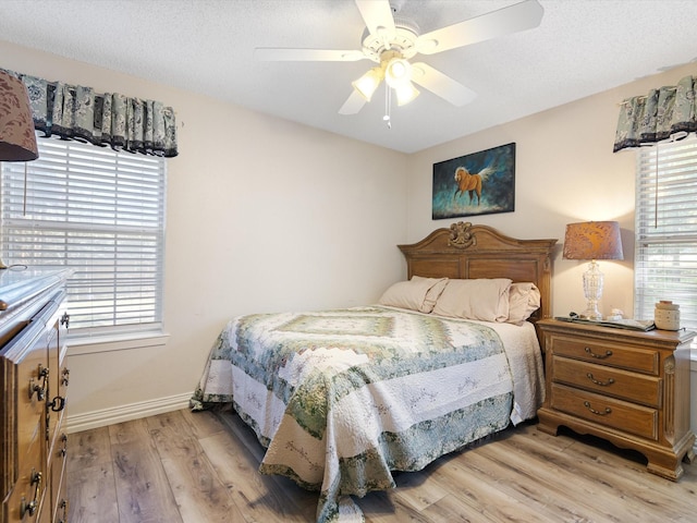 bedroom with a textured ceiling, light wood-style flooring, and baseboards