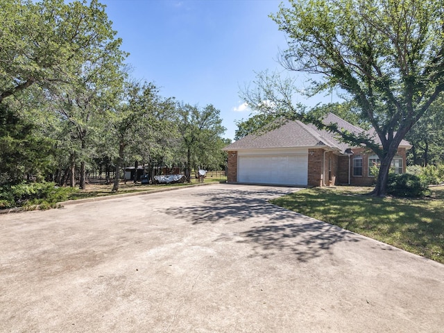 view of side of property with driveway, an attached garage, a lawn, and brick siding