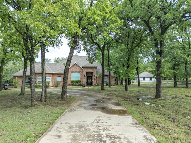 102 W Ridge St, Decatur, TX 76234 - view of front facade with curved driveway, roof with shingles, a front yard, and brick siding