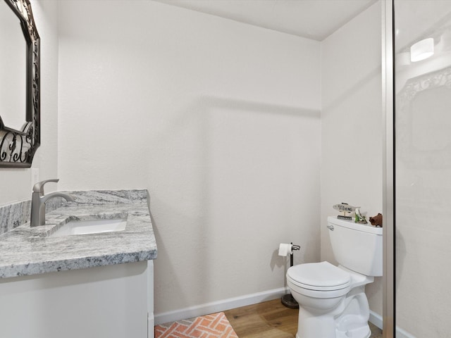 bathroom with wood finished floors, vanity, toilet, and baseboards