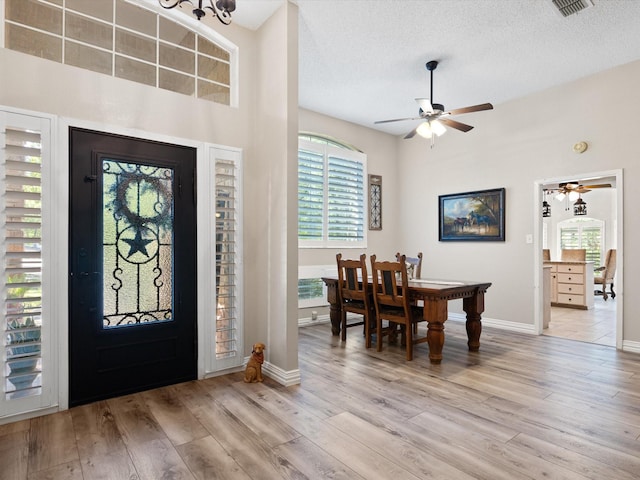 foyer entrance featuring a textured ceiling, ceiling fan, light wood-style flooring, and baseboards