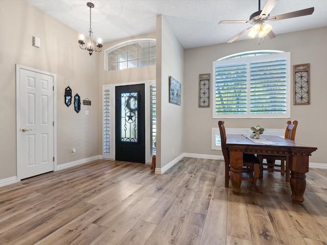 entrance foyer featuring a textured ceiling, light wood finished floors, ceiling fan with notable chandelier, and baseboards