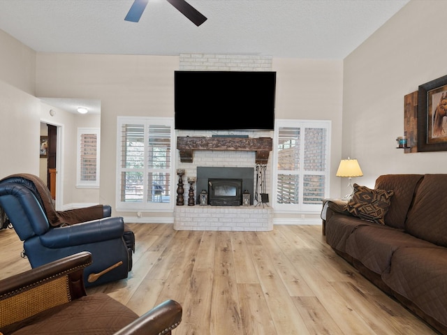 living area with a fireplace, wood-type flooring, a ceiling fan, a textured ceiling, and baseboards