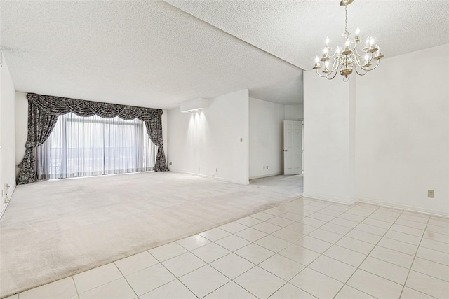 unfurnished room with light tile patterned floors, light colored carpet, a textured ceiling, a chandelier, and baseboards