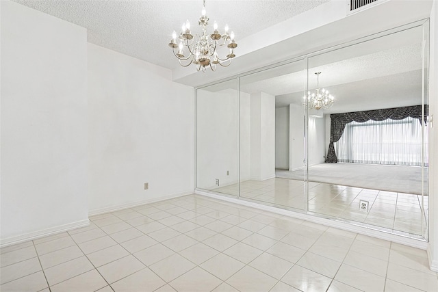 unfurnished dining area with light tile patterned floors, a textured ceiling, baseboards, and an inviting chandelier