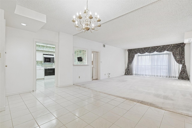 unfurnished living room with light carpet, light tile patterned floors, baseboards, a textured ceiling, and a chandelier