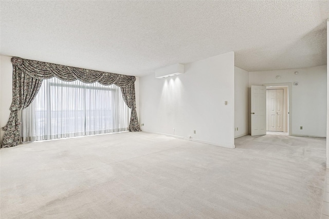 spare room featuring a textured ceiling, baseboards, and light colored carpet