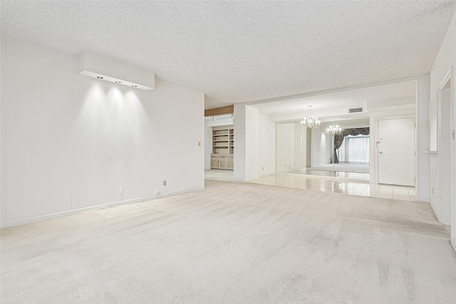 unfurnished living room with a textured ceiling, a notable chandelier, carpet floors, visible vents, and baseboards