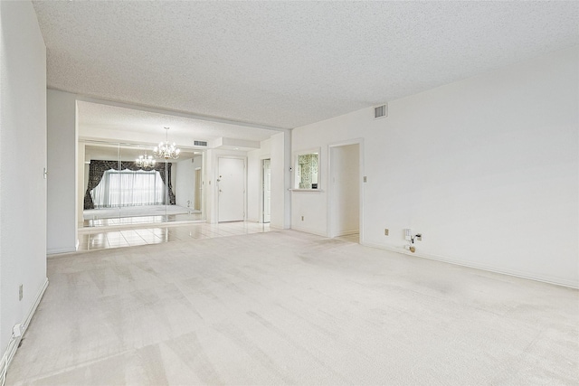 unfurnished living room featuring a chandelier, a textured ceiling, visible vents, baseboards, and carpet