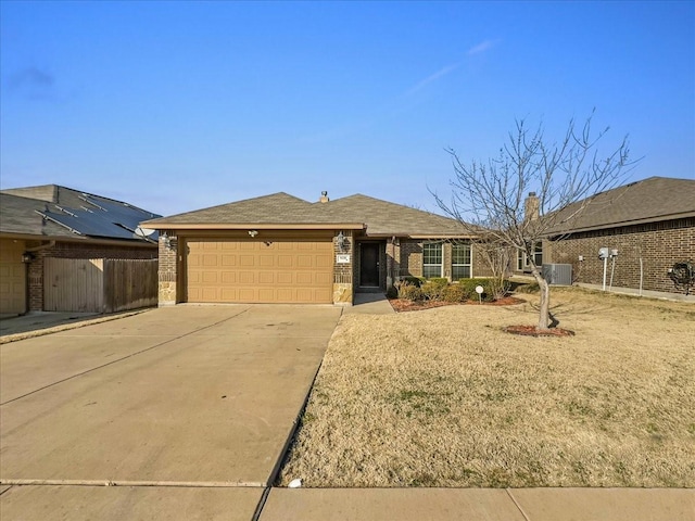 single story home featuring concrete driveway, an attached garage, fence, central air condition unit, and brick siding