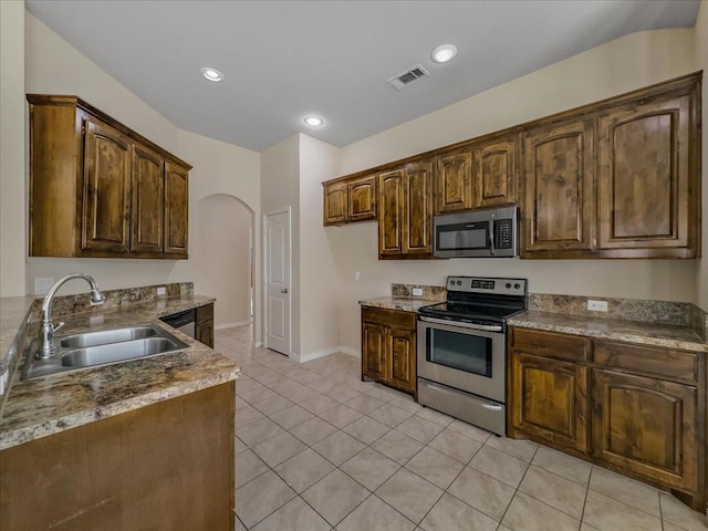 kitchen with light tile patterned floors, arched walkways, visible vents, stainless steel appliances, and a sink