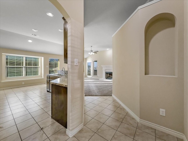 kitchen featuring open floor plan, ceiling fan, light tile patterned floors, and a sink