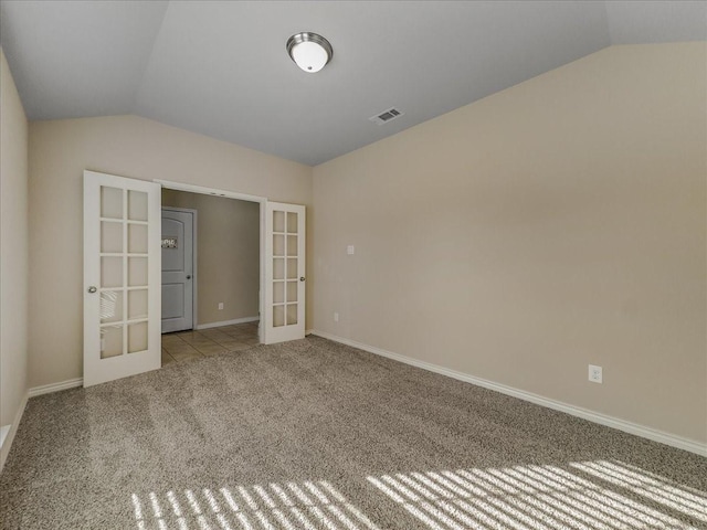 carpeted empty room with lofted ceiling, baseboards, visible vents, and french doors