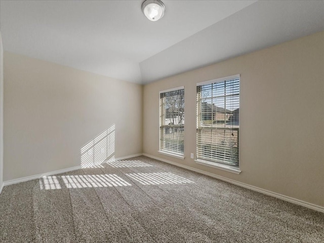 carpeted empty room with lofted ceiling and baseboards