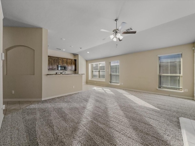 unfurnished living room with a ceiling fan, light carpet, vaulted ceiling, and baseboards