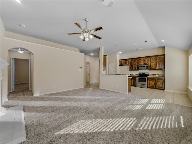 unfurnished living room featuring arched walkways, vaulted ceiling, visible vents, and light colored carpet