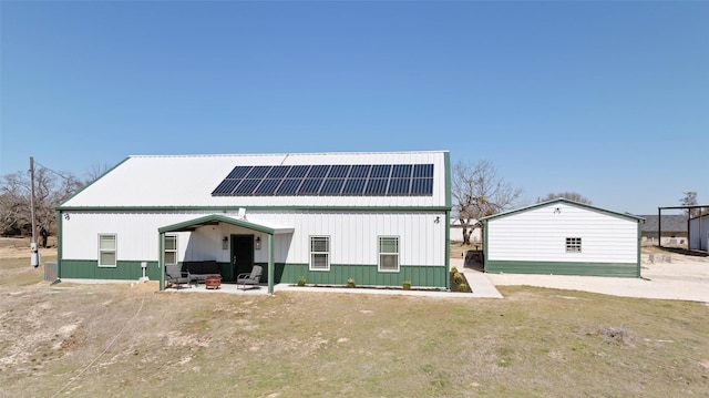 rear view of house featuring metal roof, a patio area, and roof mounted solar panels