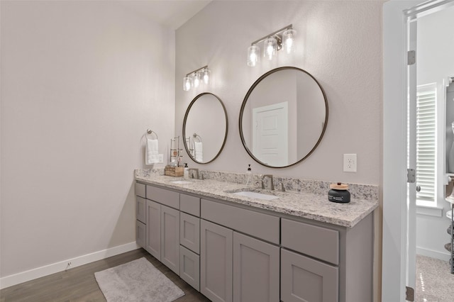 full bathroom featuring double vanity, a sink, and baseboards