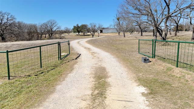 view of road featuring driveway, a rural view, a gate, and a gated entry