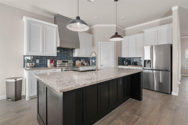 kitchen featuring light wood finished floors, appliances with stainless steel finishes, white cabinetry, a sink, and wall chimney range hood