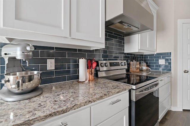 kitchen with wall chimney exhaust hood, tasteful backsplash, stainless steel range with electric stovetop, and white cabinetry