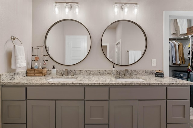 bathroom with double vanity, a spacious closet, and a sink