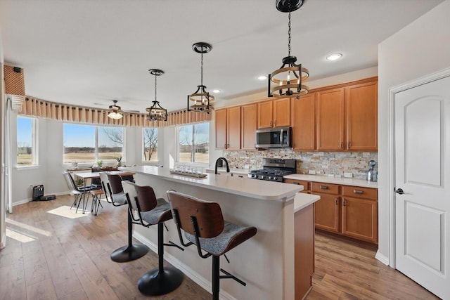 10112 Parkcrest Ct, Denton, TX 76207 - kitchen featuring a breakfast bar area, backsplash, hanging light fixtures, light countertops, and stainless steel appliances