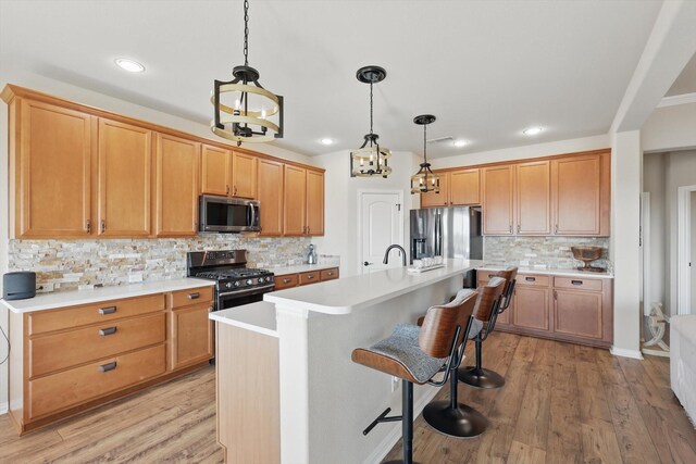 10112 Parkcrest Ct, Denton, TX 76207 - kitchen with appliances with stainless steel finishes, tasteful backsplash, light wood-type flooring, light countertops, and an island with sink