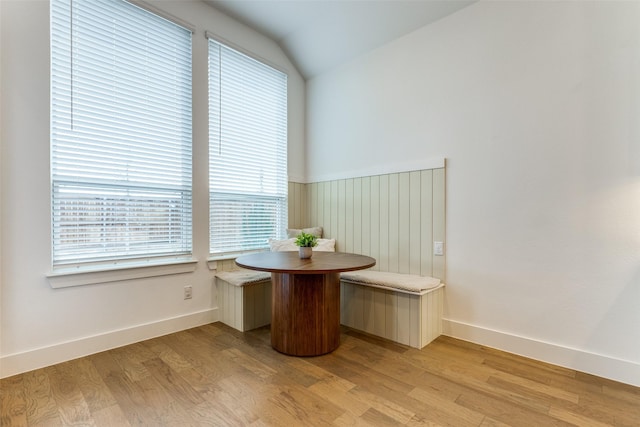 unfurnished dining area with lofted ceiling, light wood-style floors, baseboards, and breakfast area