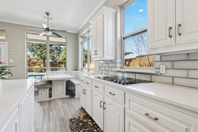5505 Lomita Cir, Plano, TX 75023 - kitchen featuring black electric cooktop, a ceiling fan, crown molding, tasteful backsplash, and white cabinetry
