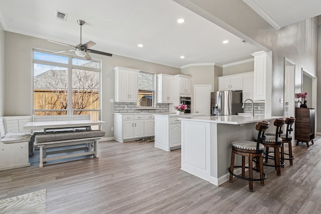 5505 Lomita Cir, Plano, TX 75023 - kitchen with appliances with stainless steel finishes, ceiling fan, a peninsula, light wood-style floors, and white cabinets