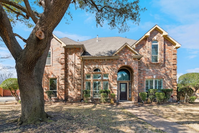 view of front of house with brick siding and roof with shingles