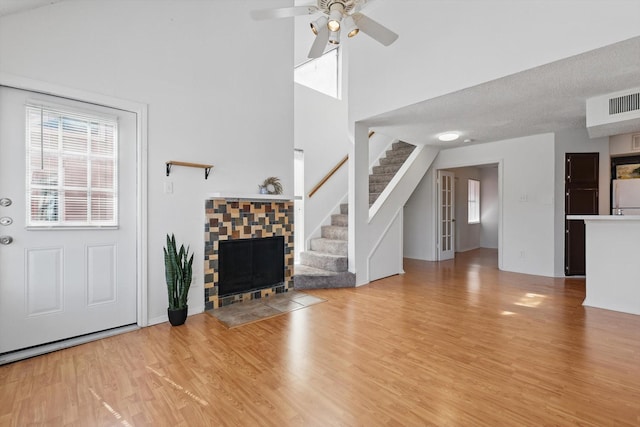 living area featuring stairs, a tiled fireplace, wood finished floors, and a ceiling fan