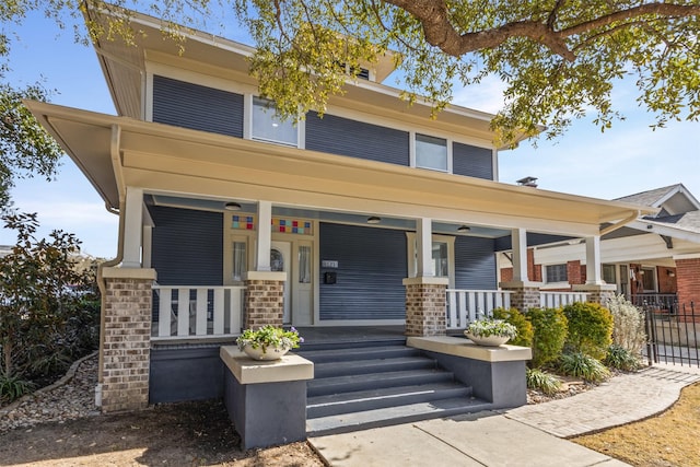 traditional style home with a porch, fence, and brick siding