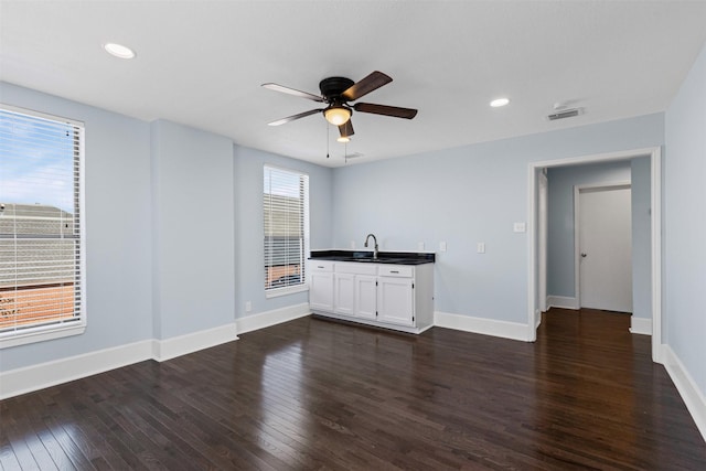 interior space featuring baseboards, visible vents, dark countertops, dark wood-style floors, and ceiling fan