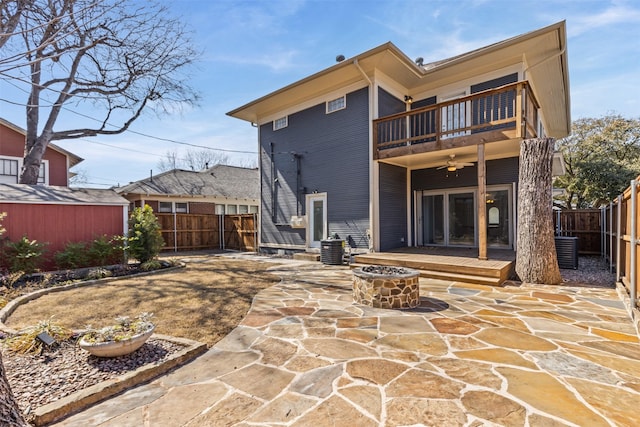 back of property with ceiling fan, a patio, an outdoor fire pit, a fenced backyard, and a balcony