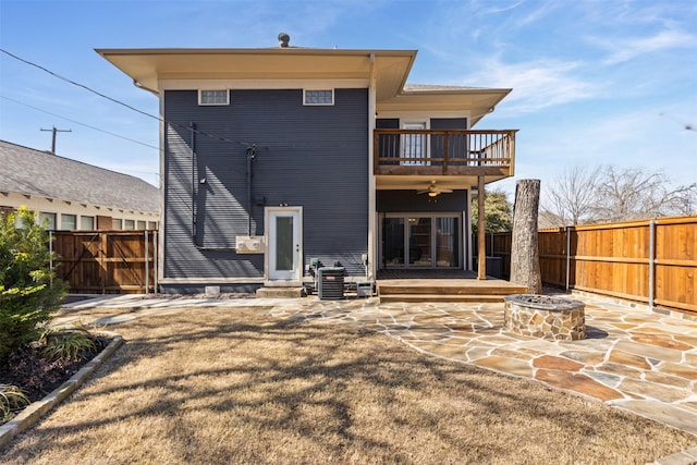 back of property featuring a fire pit, a patio area, a fenced backyard, and a balcony