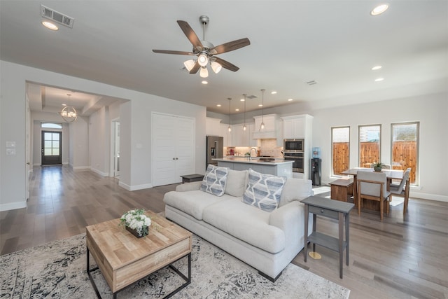 living room featuring light wood-style flooring, visible vents, baseboards, and recessed lighting