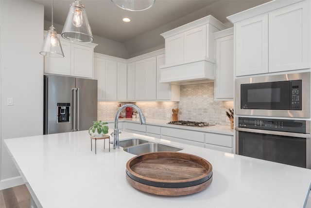 kitchen featuring appliances with stainless steel finishes, light countertops, a sink, and tasteful backsplash